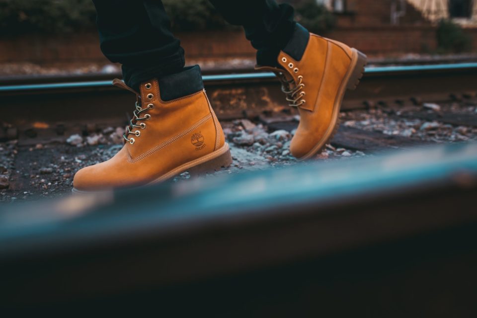 person walks along rail road with Timbalands