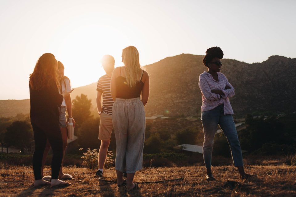 five people stand on mountainside with golden light peeking through