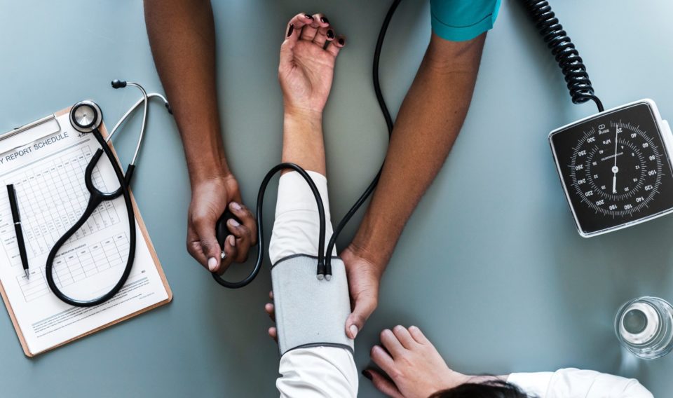 Doctor takes patient's blood pressure with cuff