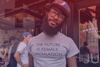 Man in front of outdoor bar wearing glasses, hat, and shirt that reads "The Future is Female Ejaculation" | Sex positive logo overlay with the word "July" at bottom right.